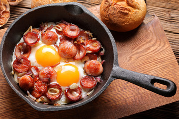 Cooked egg and sausages on frying pan