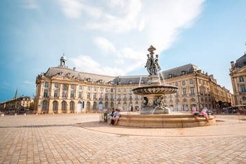 View on the famous La Bourse square with fountain in Bordeaux city, France. Long exposure image technic with motion blurred people and clouds - obrazy, fototapety, plakaty