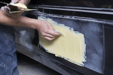 Auto body repair series: Mechanic applying putty filler