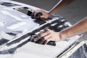 Auto body repair series: Closeup of mechanic wet-sanding car bonnet