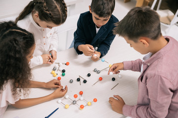 Concentrated multiethnic schoolkids studying with molecular model at chemistry lesson
