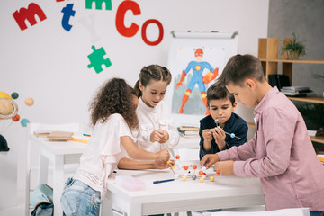 Multiethnic pupils of elementary school working with molecular model at chemistry class