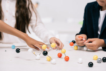 Cropped shot of schoolkids working with molecular model at chemistry lesson