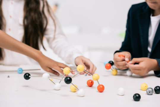 Cropped shot of schoolkids working with molecular model at chemistry lesson