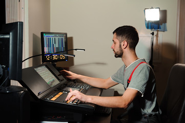 A lighting engineer works with lights technicians control on the concert show. Professional light...