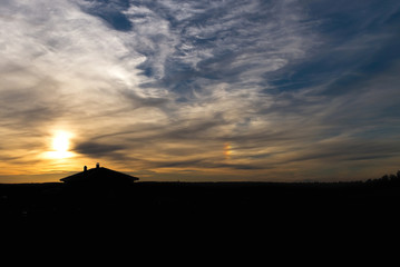 Sunset rainbow. A silhouette of country house against sunset sky.