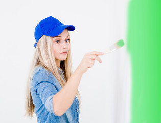 Young woman painting the wall with paintbrush