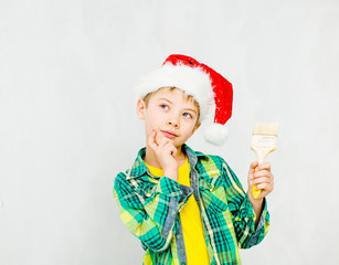 Boy in a red christmas hat with paintbrush in hand