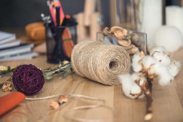 florist workplace with dry cotton flowers, twine and different supplies