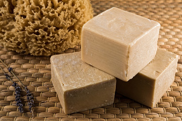 Handmade olive oil soaps, together with a natural sea sponge and a small branch of lavender
