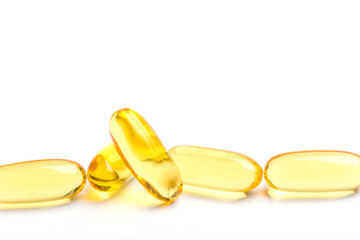 Row of golden soft gelatin capsules common use for natural essential oil supplements, isolated on white background.