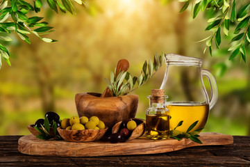 Freshly harvested olives berries in wood bowls and pressed oil in glass bottles