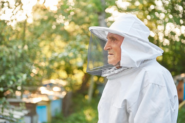 Profile portrait of a senior man in beekeeping suit posing outdoors copyspace beekeeper profession occupation hobby lifestyle farmer farming concept.