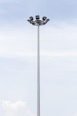 Sportlights tower in stadium with cloudy blue sky in background.