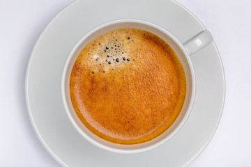 Hot black coffee with foam bubbles in white cup with white background, morning coffee concept.