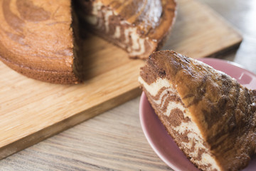 Homemade zebra pie on a wooden board and a piece of cake on a saucer