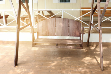 wooden swing with backrest on patio light effect from left side