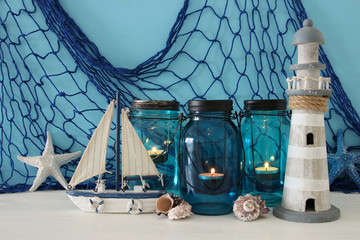 Obraz na płótnie Canvas Magical mason jars whith candle light and wooden boat on the shelf. Nautical concept