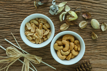 Roasted cashew nuts and peanuts appetizer in white bowl on wooden table background