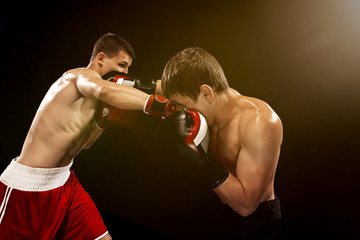 Plakat Two professional boxer boxing on black background,