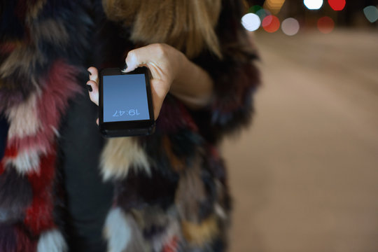Close up of woman's hand wearing multicolour fur holding mobile phone