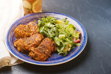 Platter of chicken thighs piri piri coated in hot sauce with salad.