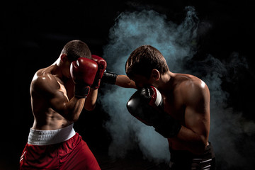 Two professional boxer boxing on black smoky background, - obrazy, fototapety, plakaty