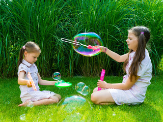 Children playing with soap bubble wand in the park on a sunny summer day