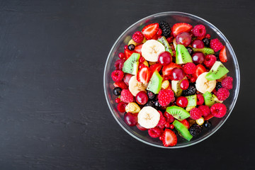 Fruit salad in glass plate on dark background. Flat lay, top view