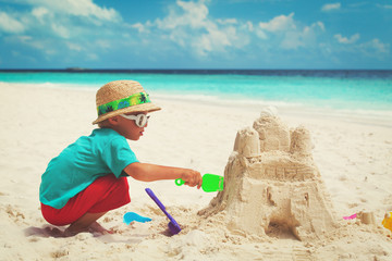 little boy building sand castle on beach