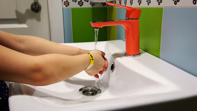 A Child Washes His Hands Under An Orange Mixer