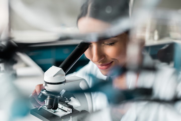 Professional young scientist working with microscope in chemical lab