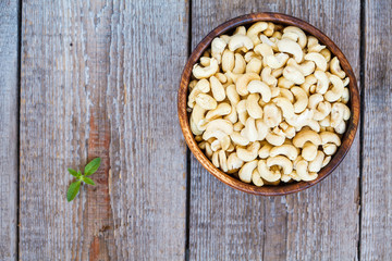 Raw cashew nut in a wooden bowl. Vegetable protein, dietary snack, top view.