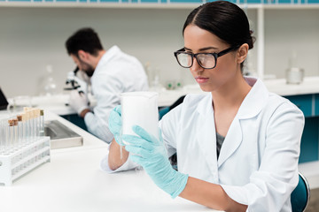 Concentrated young scientist in eyeglasses working in chemical laboratory