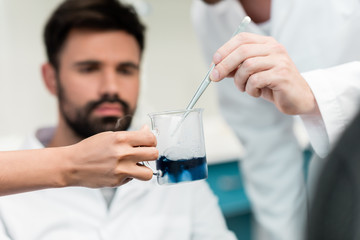 Close-up view of scientists making experiment with reagent and pipette