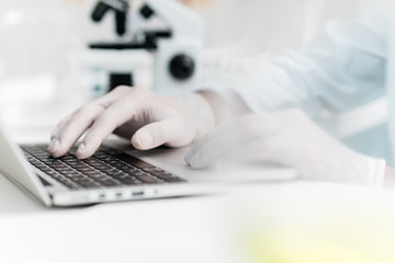 Close-up partial view of scientist using laptop in laboratory