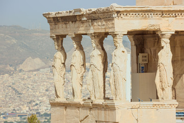 Obraz premium Sculptures of the Old Athena Temple on the Acropolis Hill with Athens out of focus in the background. Selective focus on the temple.