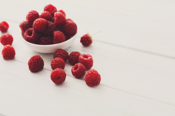 Red fresh raspberries on white rustic wood background
