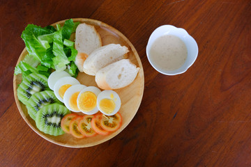 Top view of Sliced egg salad serve with vegetable, kiwi, tomato, crispy bread and separated sesame dressing
