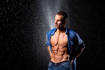 wet fitness muscular male model standing on rain