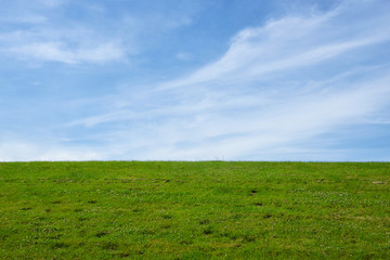 Fototapeta premium Dike with green Meadow and blue sky