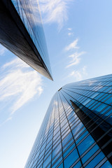 Low angle view of skyscrapers and glass buildings with blue sky in a geometric arrangement.