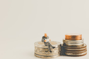 Miniature people business concept sitting on coins with a space for text