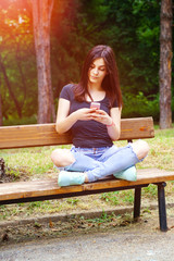 Modern woman looking at smartphone texting, making selfie or talking smiling happy in park. Beautiful young Caucasian, white young woman.