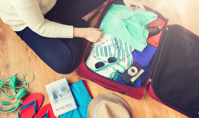 close up of woman packing travel bag for vacation