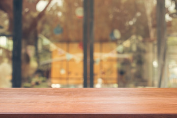Wooden board empty table top on of blurred background. Perspective brown wood table over blur in coffee shop background - can be used mock up for montage products display or design key visual layout.