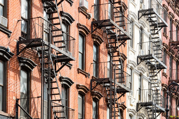 Naklejka premium Widok zewnętrzny budynków mieszkalnych w stylu Nowego Jorku z oknami i schodami przeciwpożarowymi