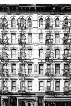 Fototapeta New York City vintage apartment building with windows and fire escapes in black and white