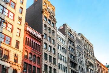 Obraz premium Wiersz wysokich zabytkowych budynków w popołudniowym słońcu wzdłuż Broadwayu na Manhattanie, Nowy Jork