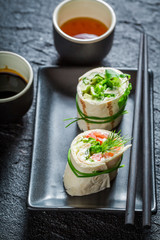 Delicious rolls with salmon, cheese and vegetables on dark rock
